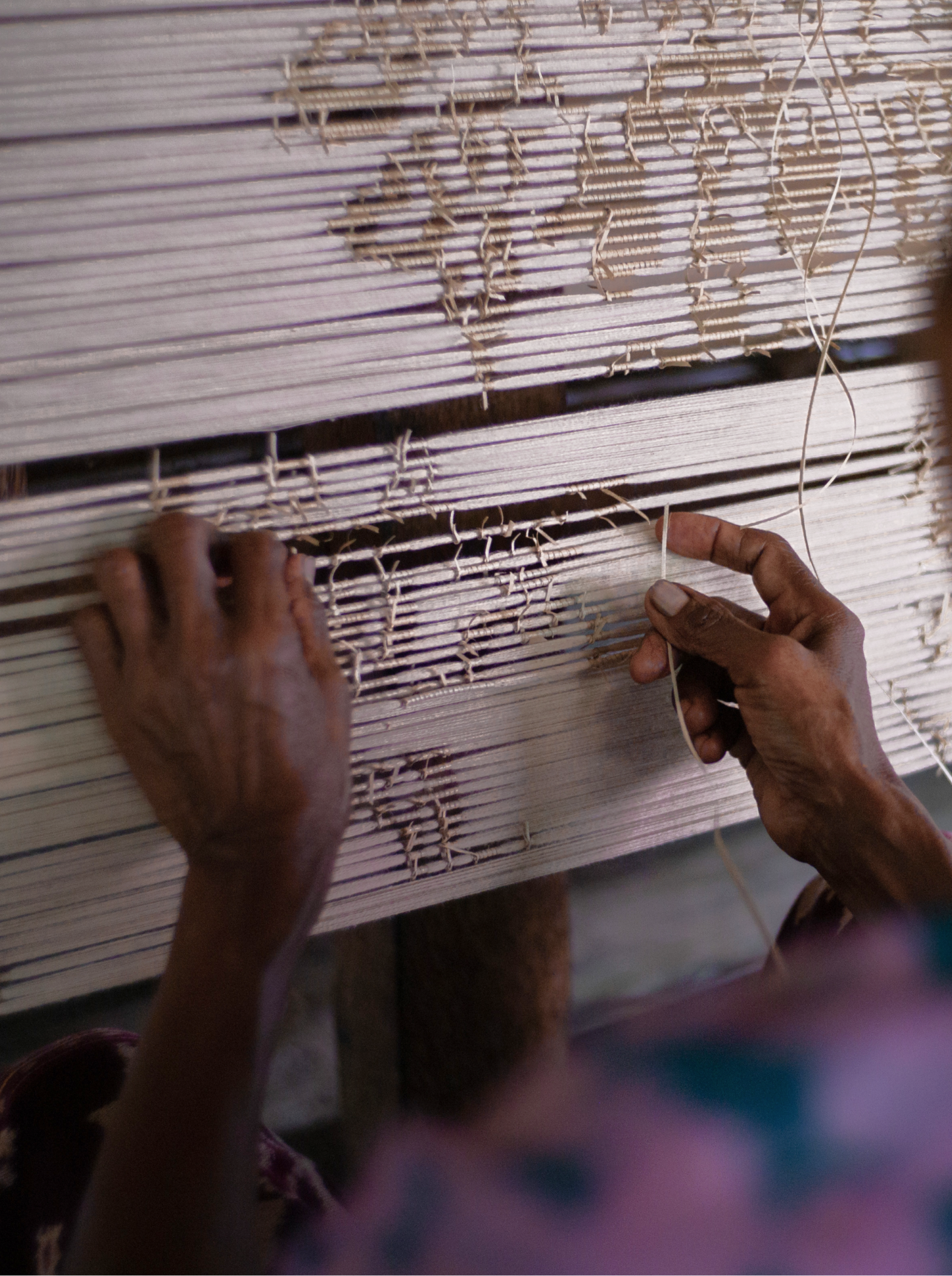 A close-up photograph of a masterful woman weaver at work