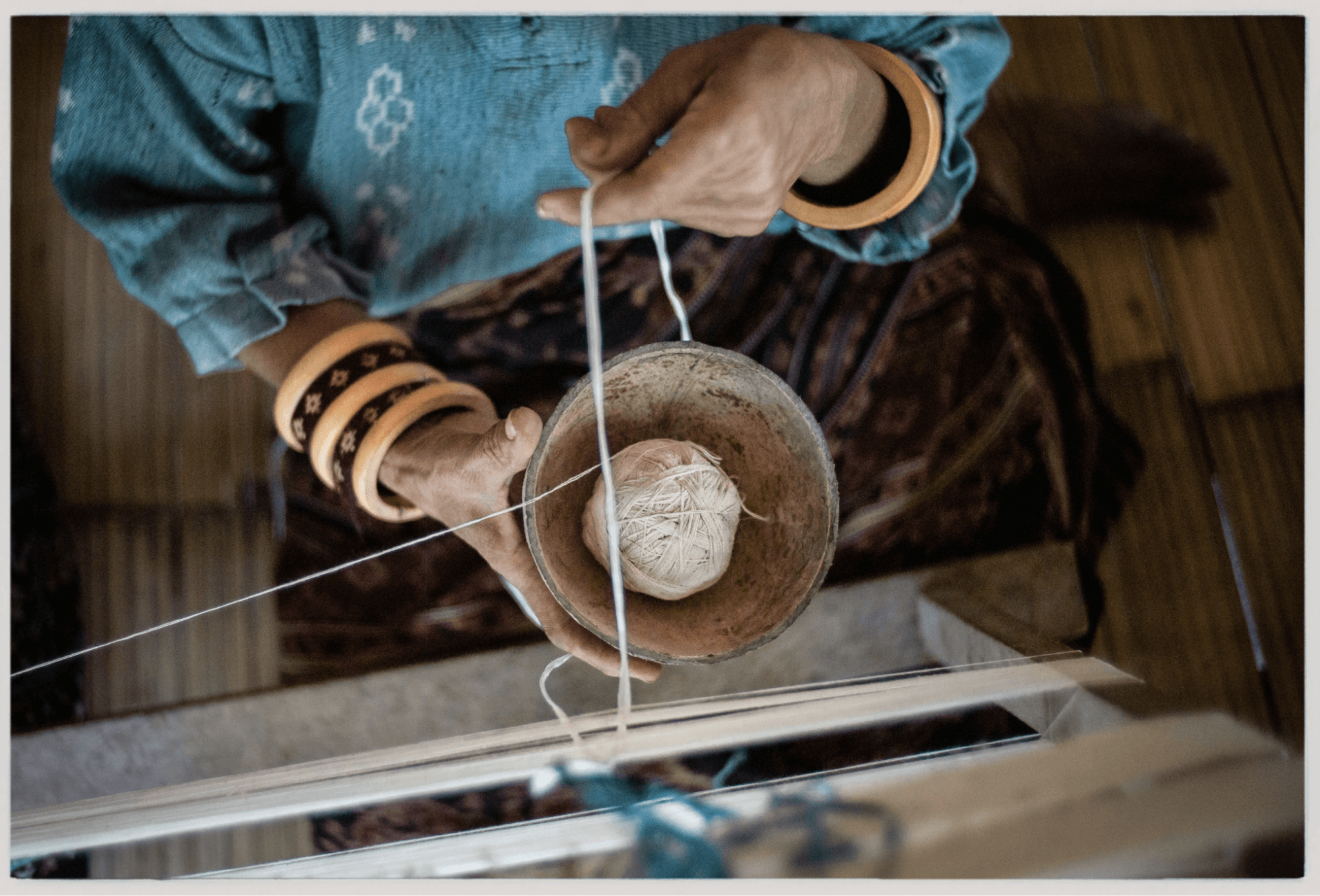 A top-down shot of a woman weaver with a bowl of yarn