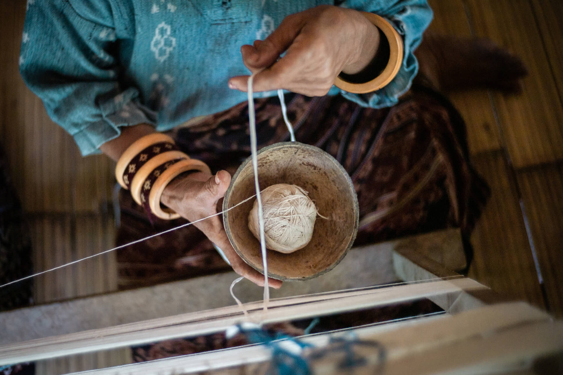Top down shot of a woman holding a bowl with a ball of thread
