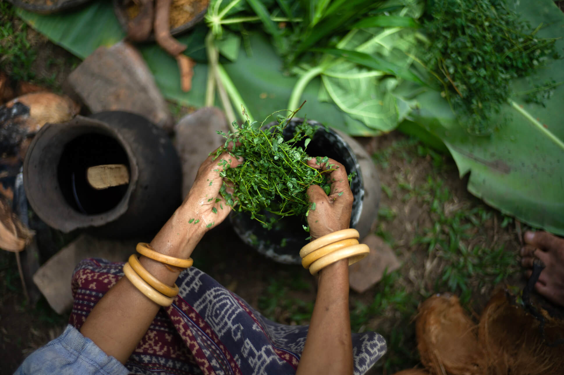 Top down shot of a woman grinding fresh herbs with a pestle and mortar